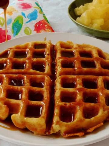 pina colada waffles with rum sauce being drizzled over them