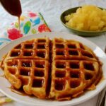 pina colada waffles on a plate, with rum sauce drizzled on top