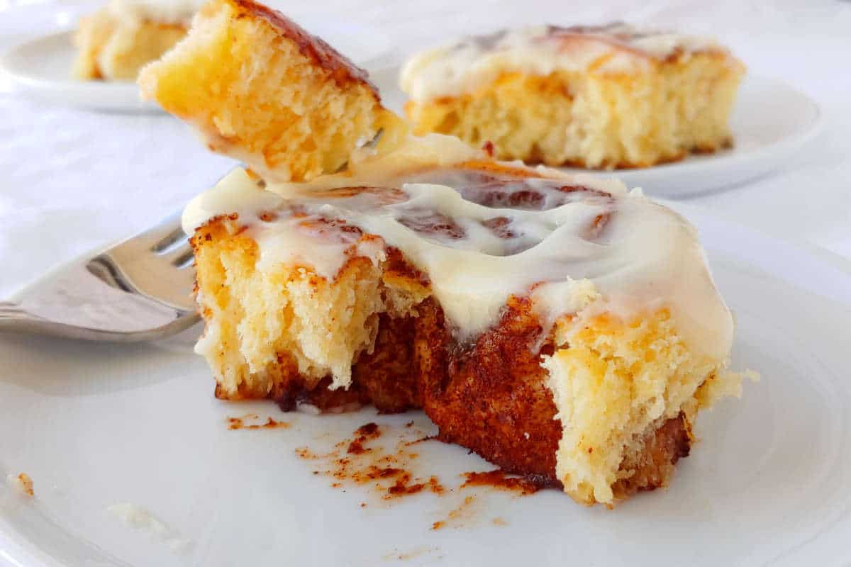 cinnamon rolls with cream cheese glaze, with a piece on a fork