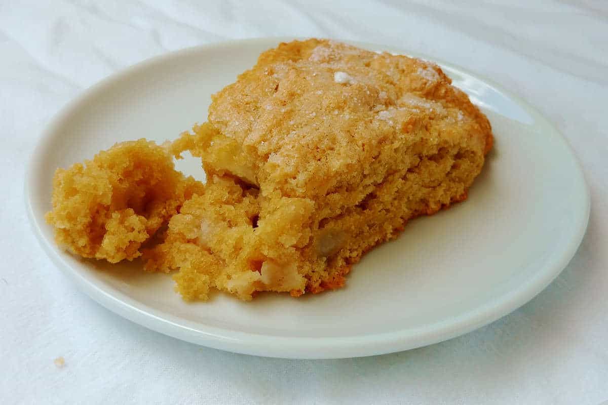 apple and pear scone, on a plate, with a piece broken off