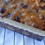 A miniature loaf of Alton Brown's fruitcake, in a brown paper liner