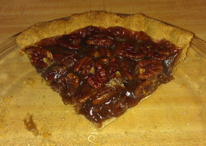 a slice of vegan pecan pie, in a glass pie pan