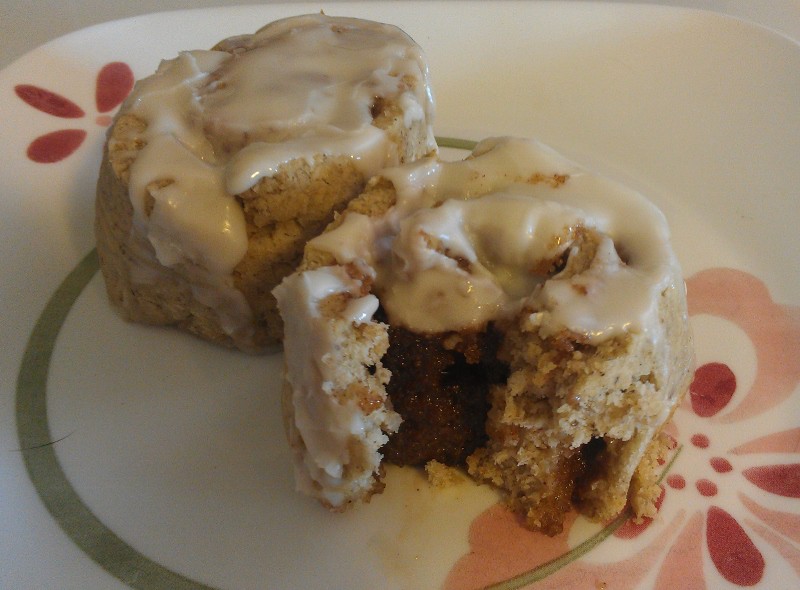 gluten-free vegan cinnamon rolls, glazed on a plate, with a bite taken from them