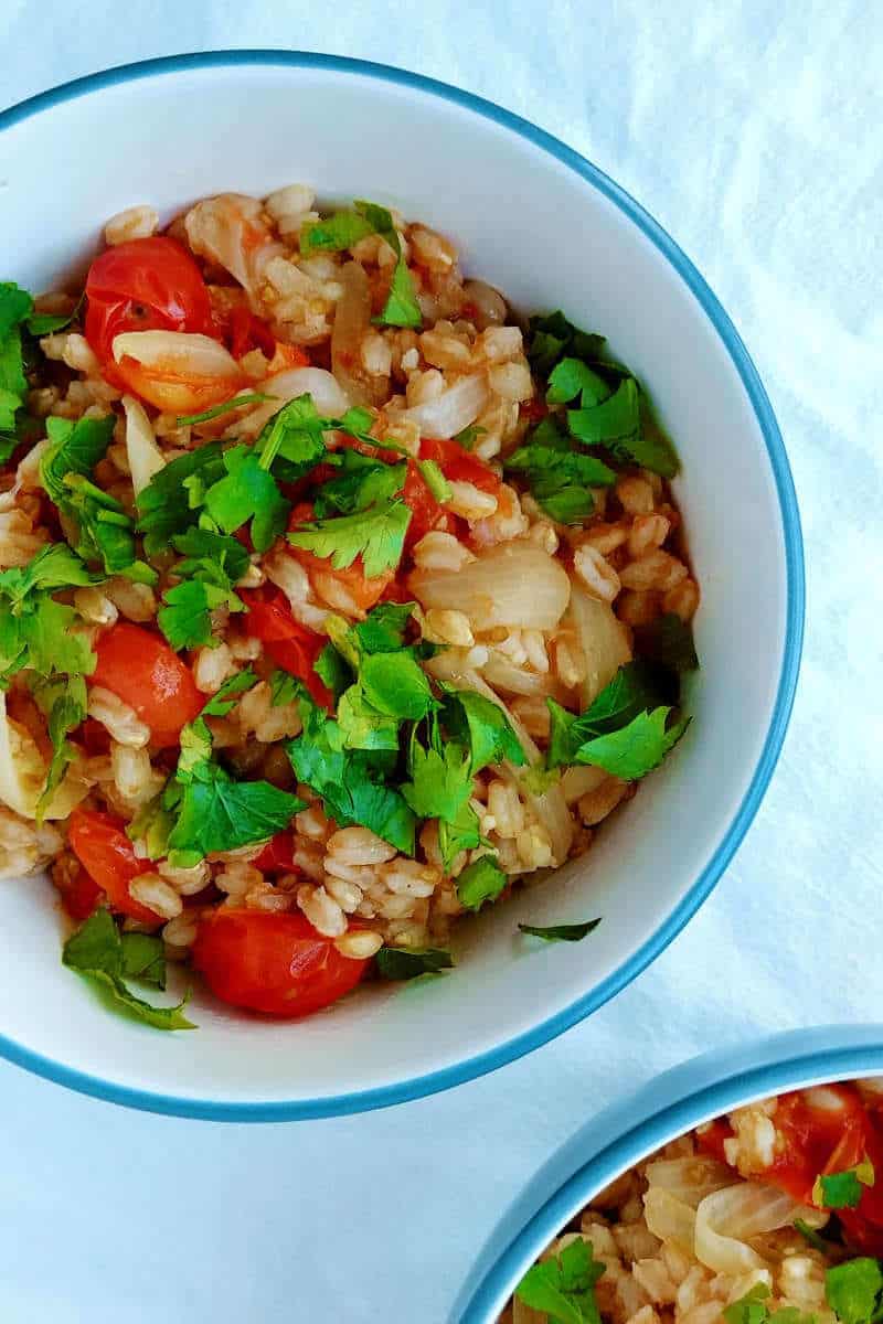 one-pot farro with tomatoes, in a bowl, garnished with parsley