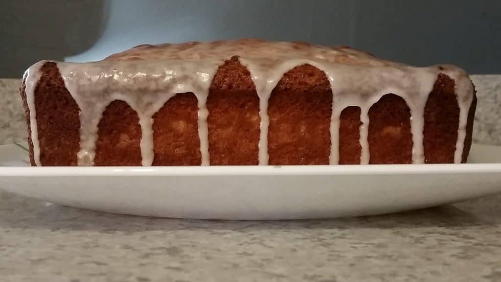 grapefruit yogurt cake, on a plate, with glaze drizzled down the sides