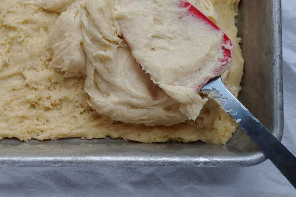 gooey layer for cinnamon gooey butter cake, being spread over cookie dough layer