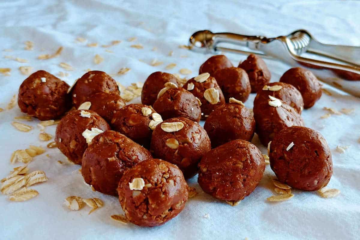 chocolate peanut butter bites, sprinkled with oats, with a scoop in the background