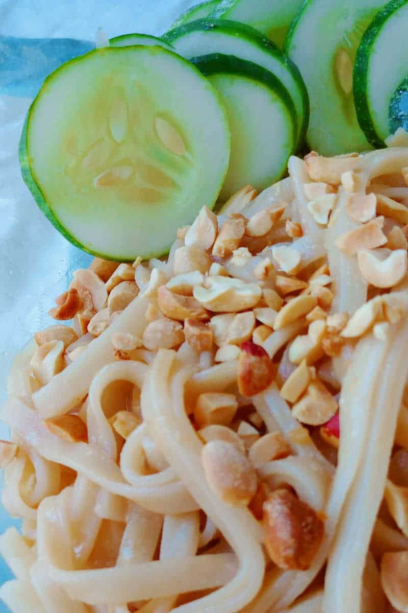 sesame noodles, topped with peanuts and cucumbers, up close