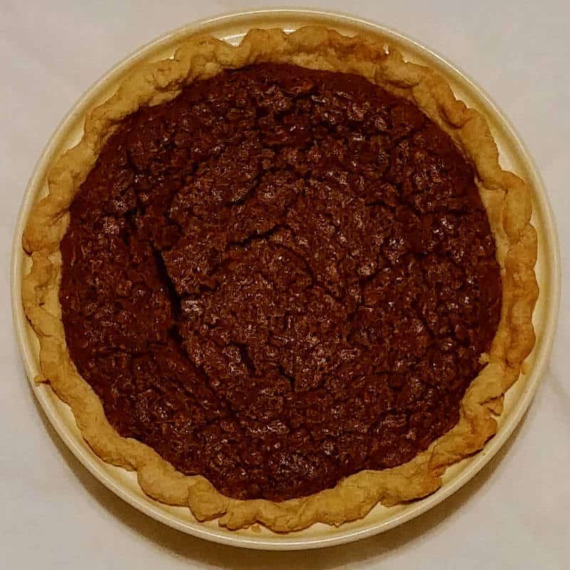a whole pecan fudge pie, in a ceramic pie plate