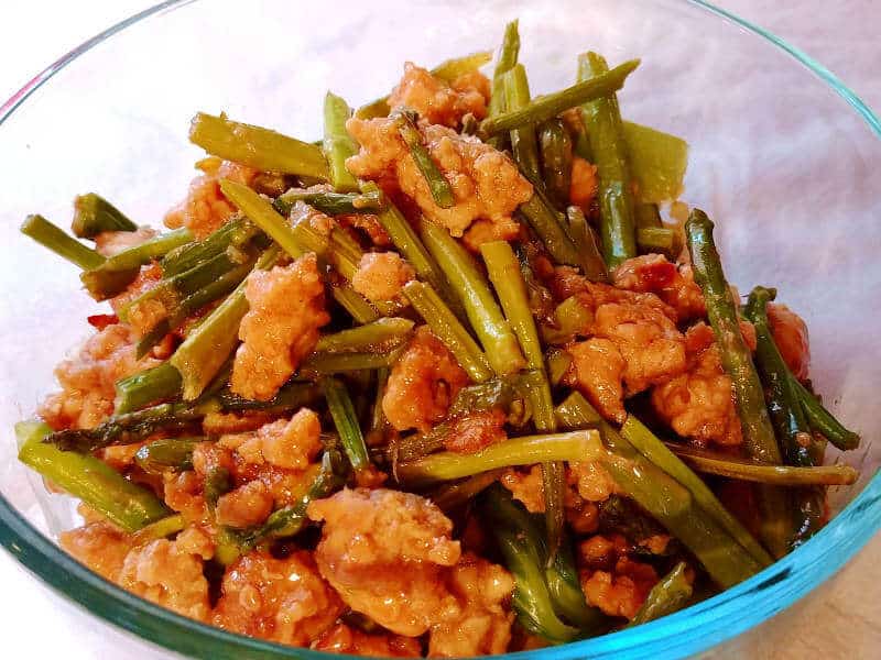 spicy pork with asparagus, in a bowl over rice