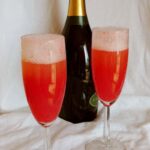 two strawberry bellinis with a bottle of sparkling wine