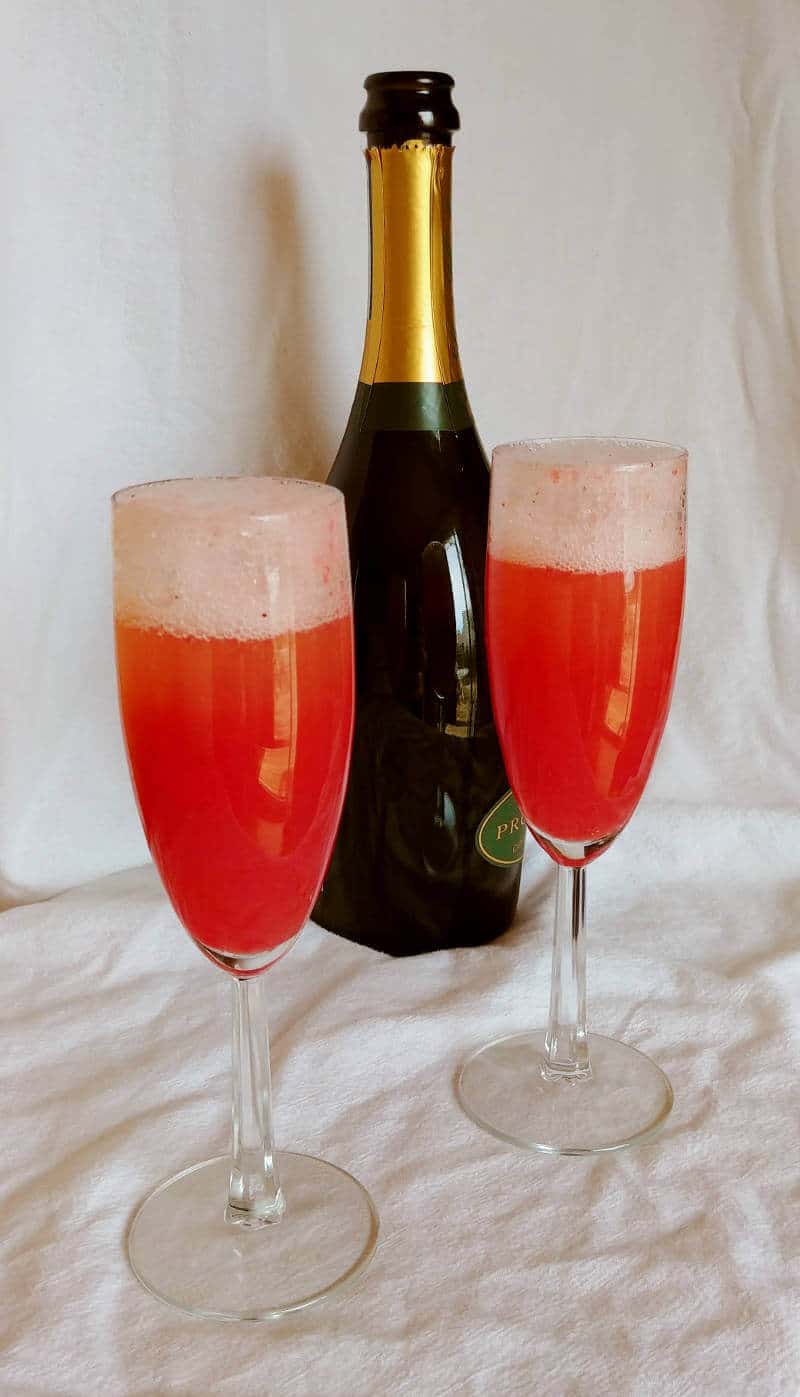 two strawberry bellinis with a bottle of sparkling wine