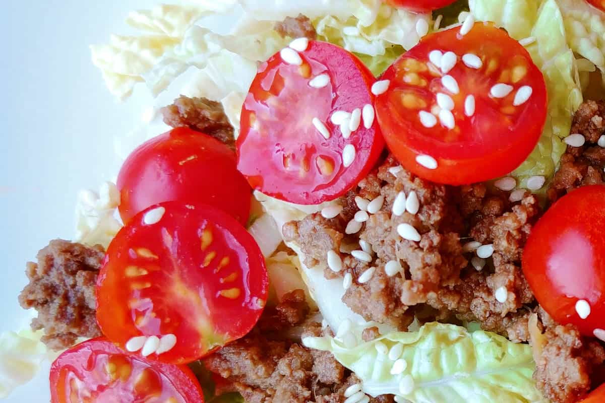 bulgogi tacos, with ground beef, tomatoes, lettuce, and sesame seeds