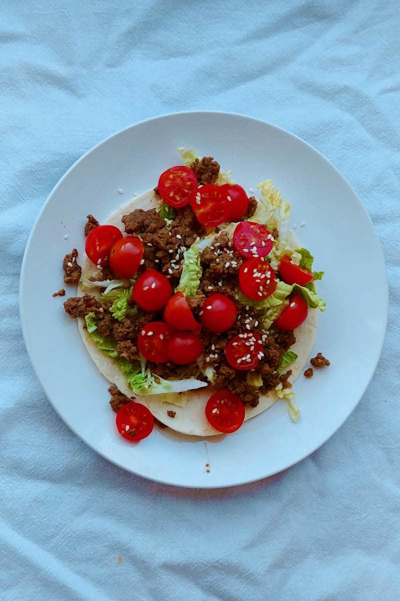 bulgogi tacos, with ground beef, tomatoes, lettuce, and sesame seeds