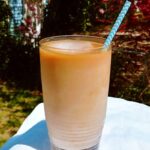 cold brew coffee concentrate, mixed with milk and ice, in a glass with a straw, outside