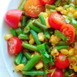 corn and green bean salad with tomatoes and lime dressing, close-up, on a plate