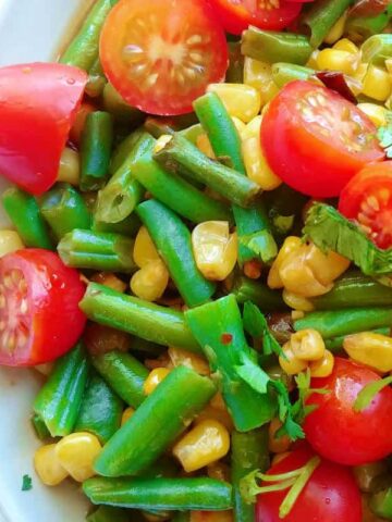 corn and green bean salad with tomatoes and lime dressing, close-up, on a plate