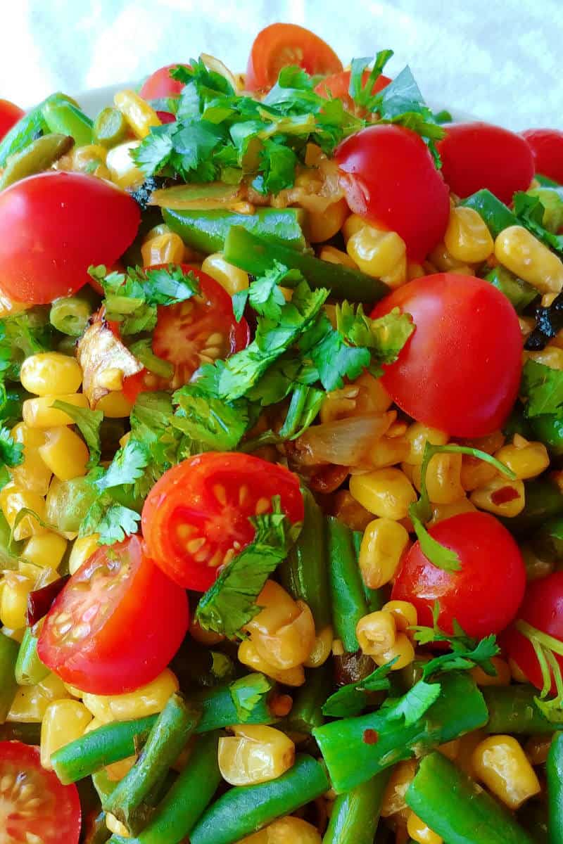 corn and green bean salad with tomatoes and lime dressing, close-up, on a plate