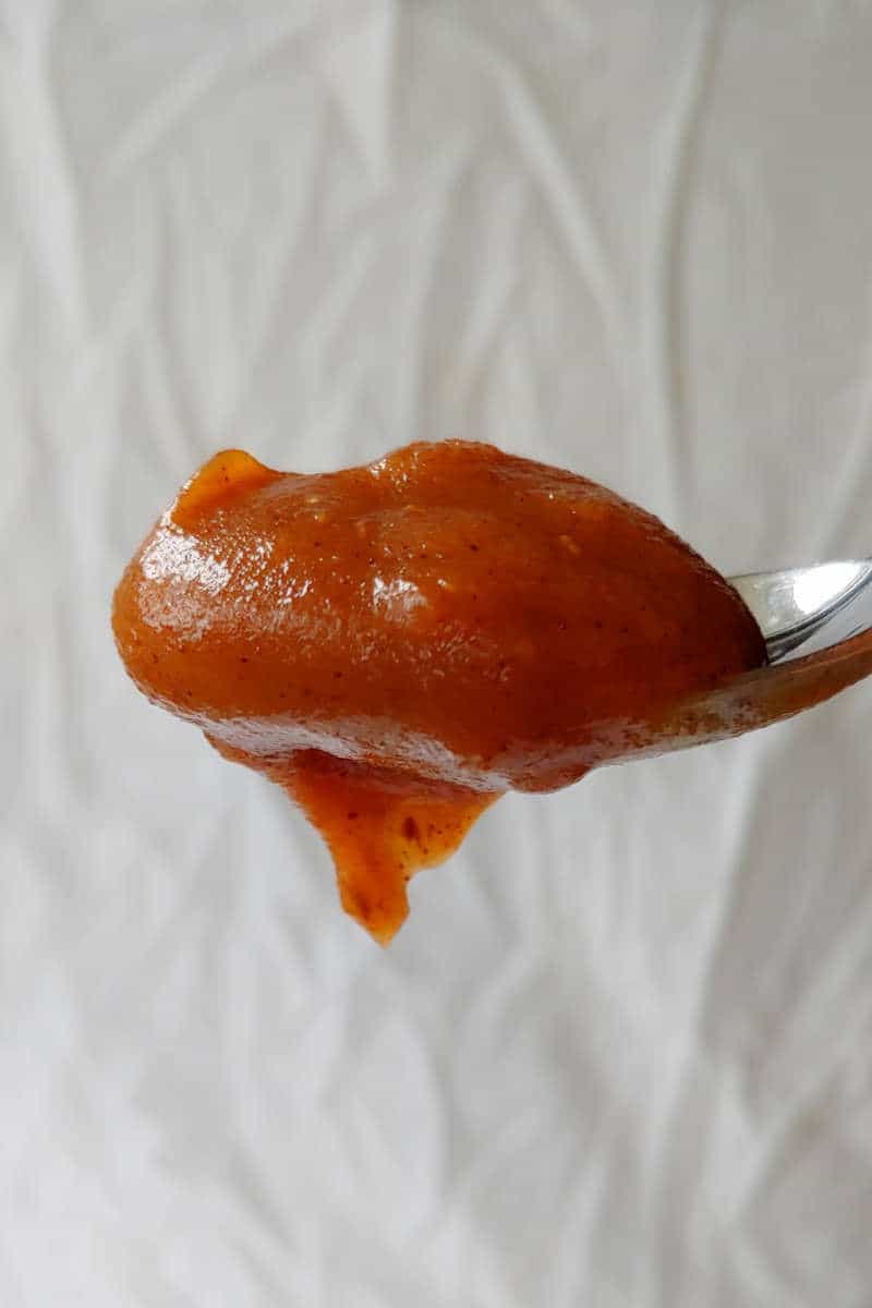 slow cooker apple butter with no sugar added, on a spoon