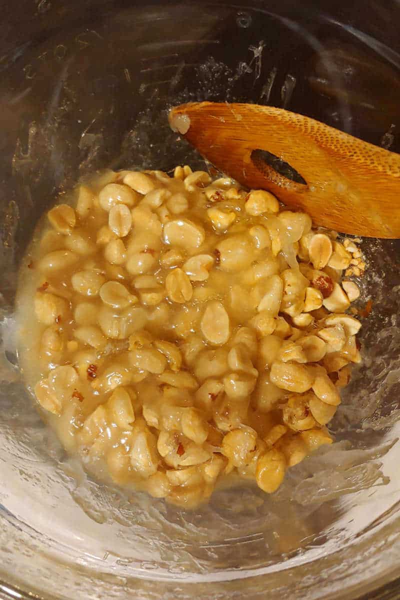 peanuts and butter being stirred into syrup for microwave peanut brittle