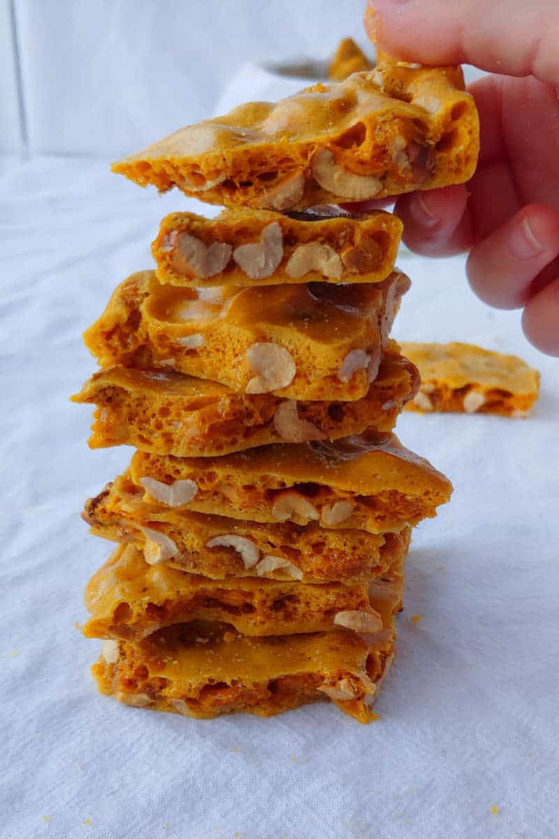 https://easyascookies.com/wp-content/uploads/2018/12/microwave-peanut-brittle-stack-hand.jpg