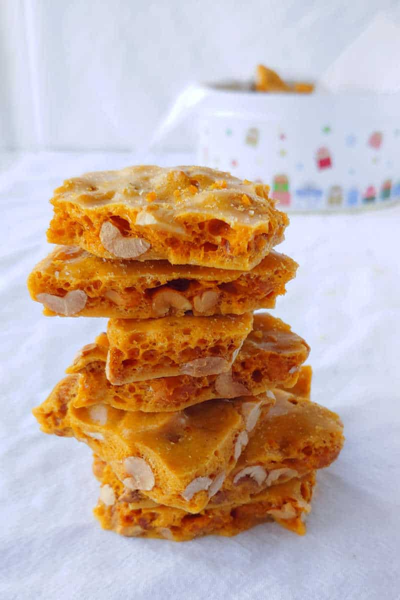 a stack of microwave peanut brittle, with a tin in the background