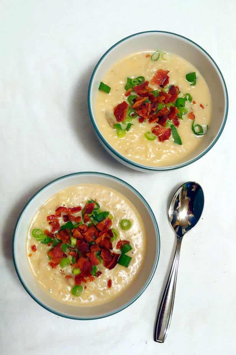 baked potato bacon soup, in 2 bowls, with a spoon