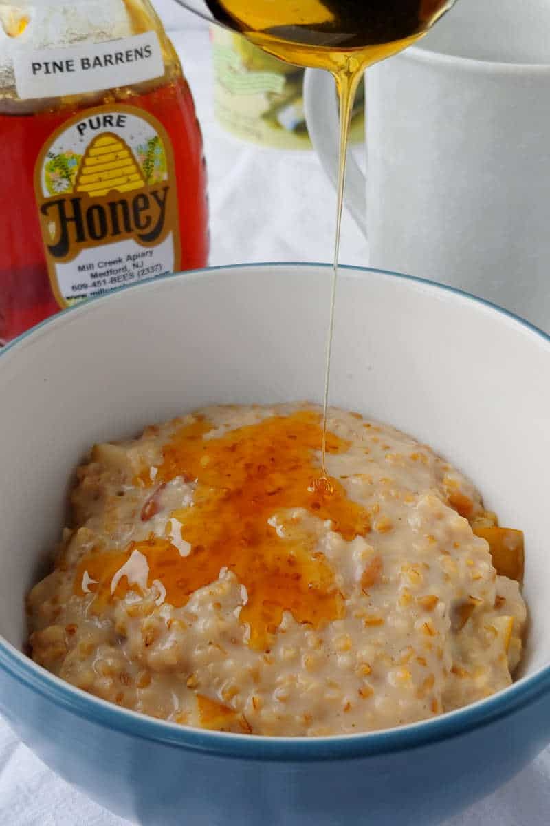 steel-cut oats with walnuts and pear, with honey being drizzled on top