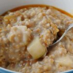 steel-cut oats with walnuts and pear, in a bowl, with a spoon and honey