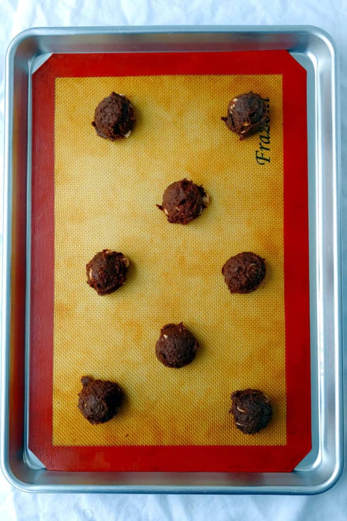 balls of double chocolate caramel chip cookies, unbaked, on a cookie sheet