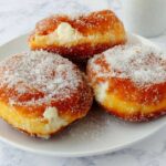 3 paczkis on a plate, coated with sugar