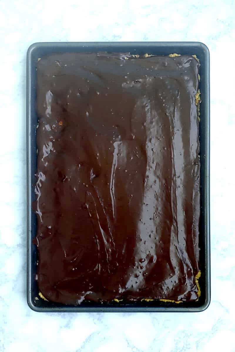 chocolate fudge layered on oatmeal cookie dough in a baking pan
