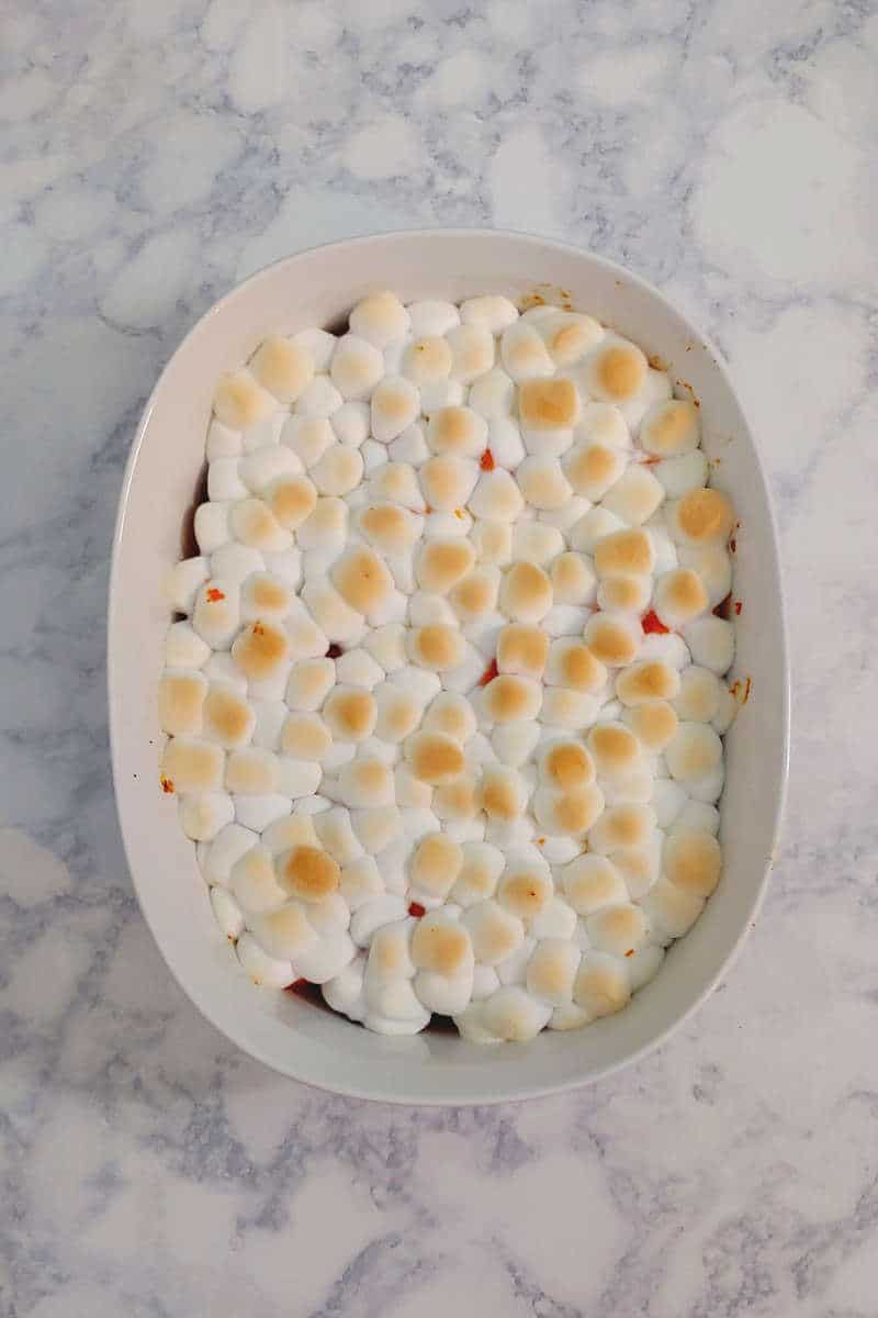 sweet potatoes topped with marshmallows that have started to brown, in a baking dish