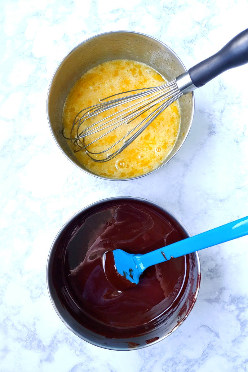 a bowl of sugar and eggs, next to a bowl of melted butter and chocolate