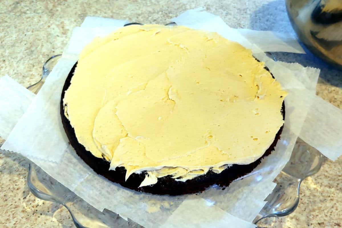 chocolate cake layer topped with peanut butter frosting; plate lined with waxed paper