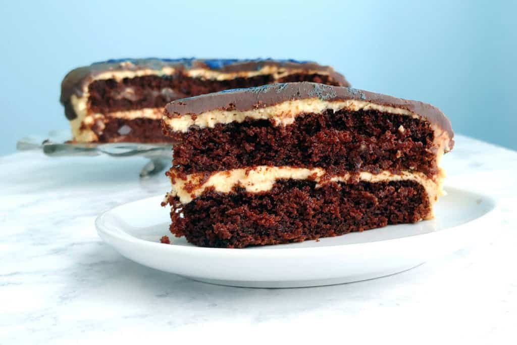 a slice of chocolate peanut butter cake, with the whole cake in background