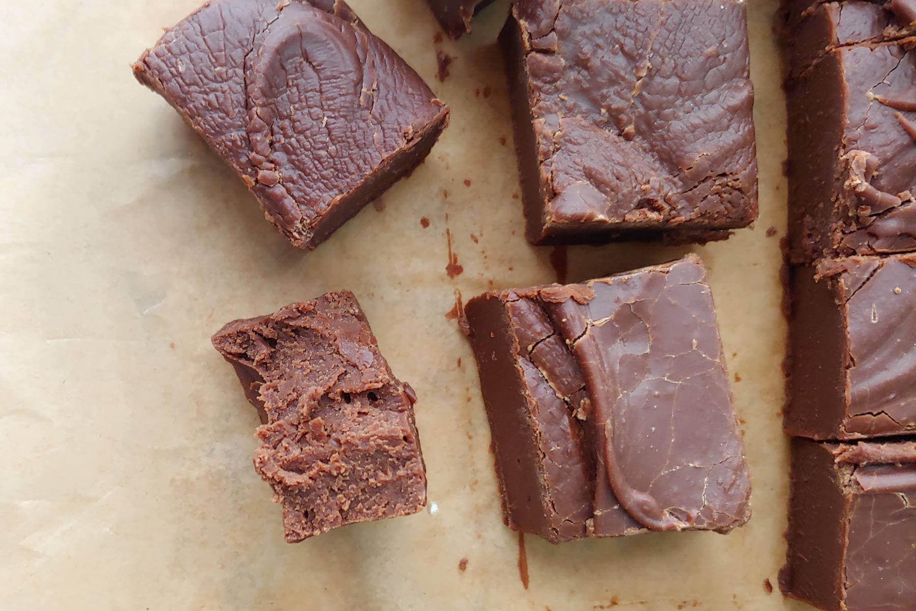 a piece of fudge, torn open to see creamy texture, alongside other squares of fudge