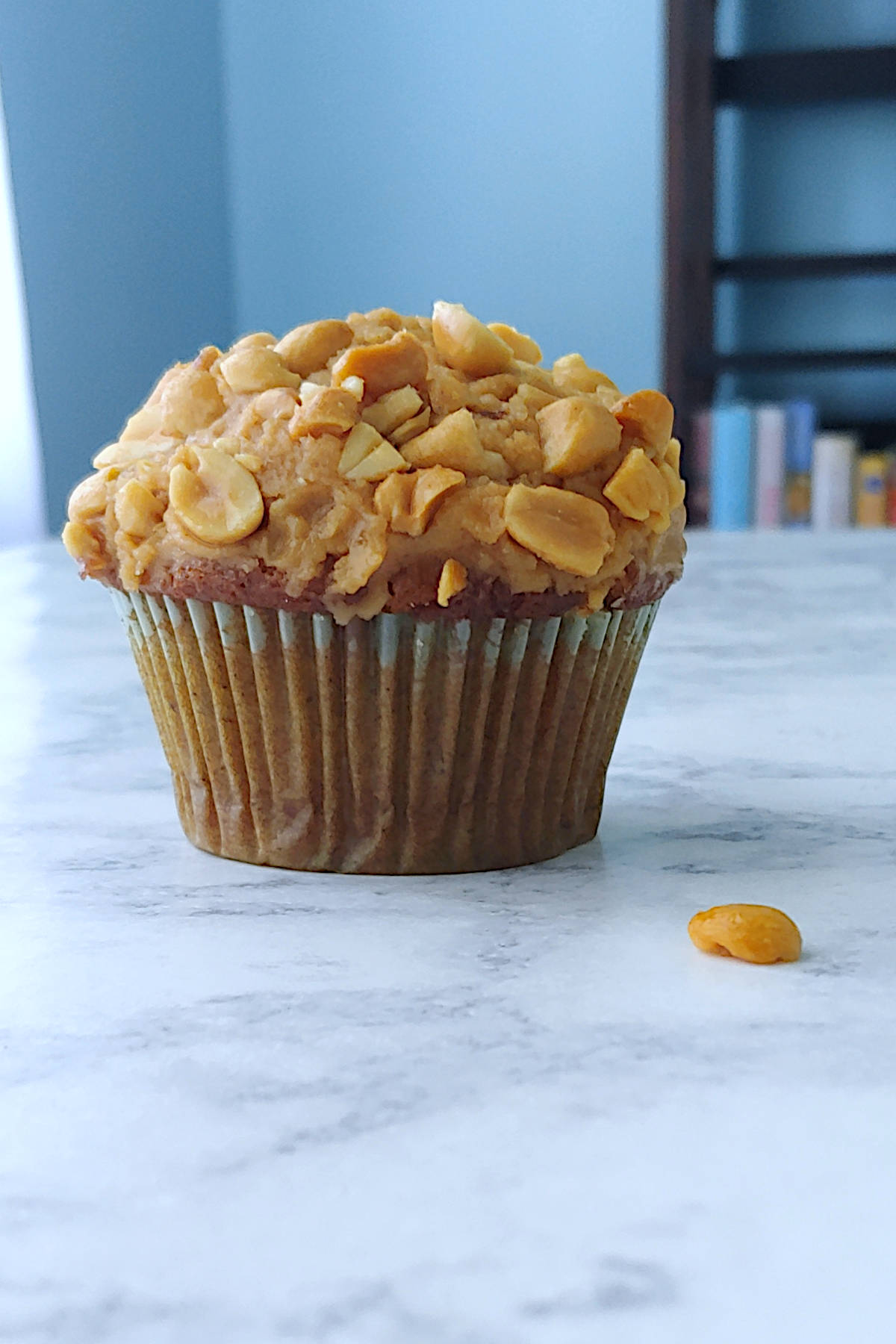 banana cupcake with peanut butter frosting, in front of a bookshelf