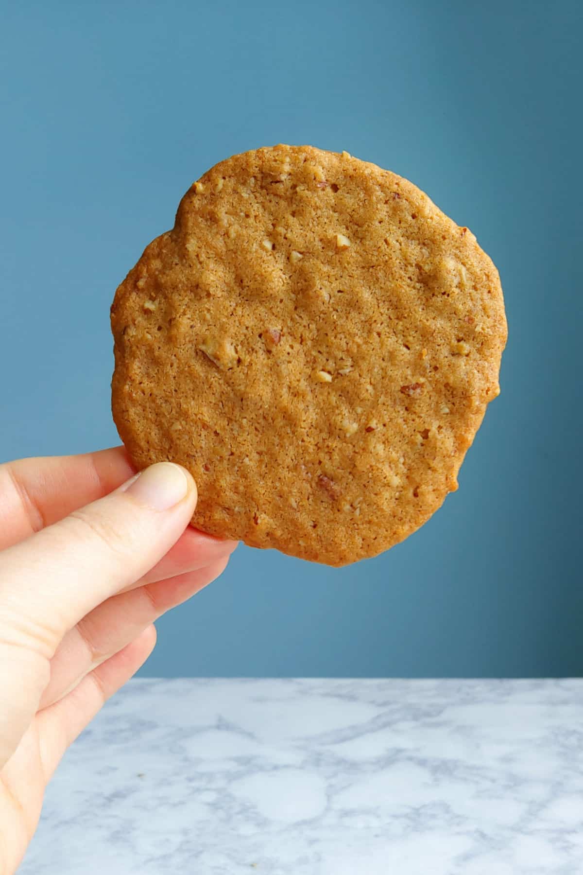 a butterscotch cookie held against a blue background