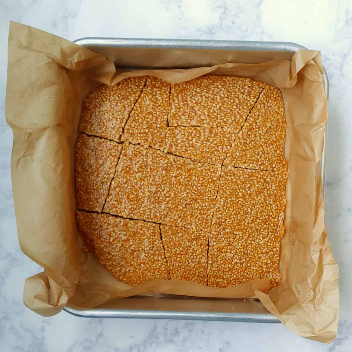 cooled sesame brittle in a pan, cracked into large pieces