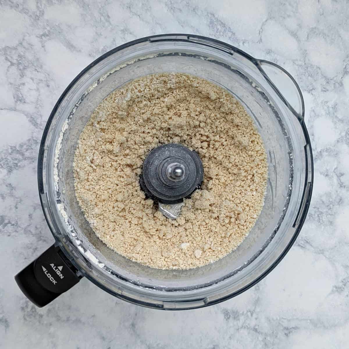all ingredients for pie crust, blitzed together into crumbles, in a food processor