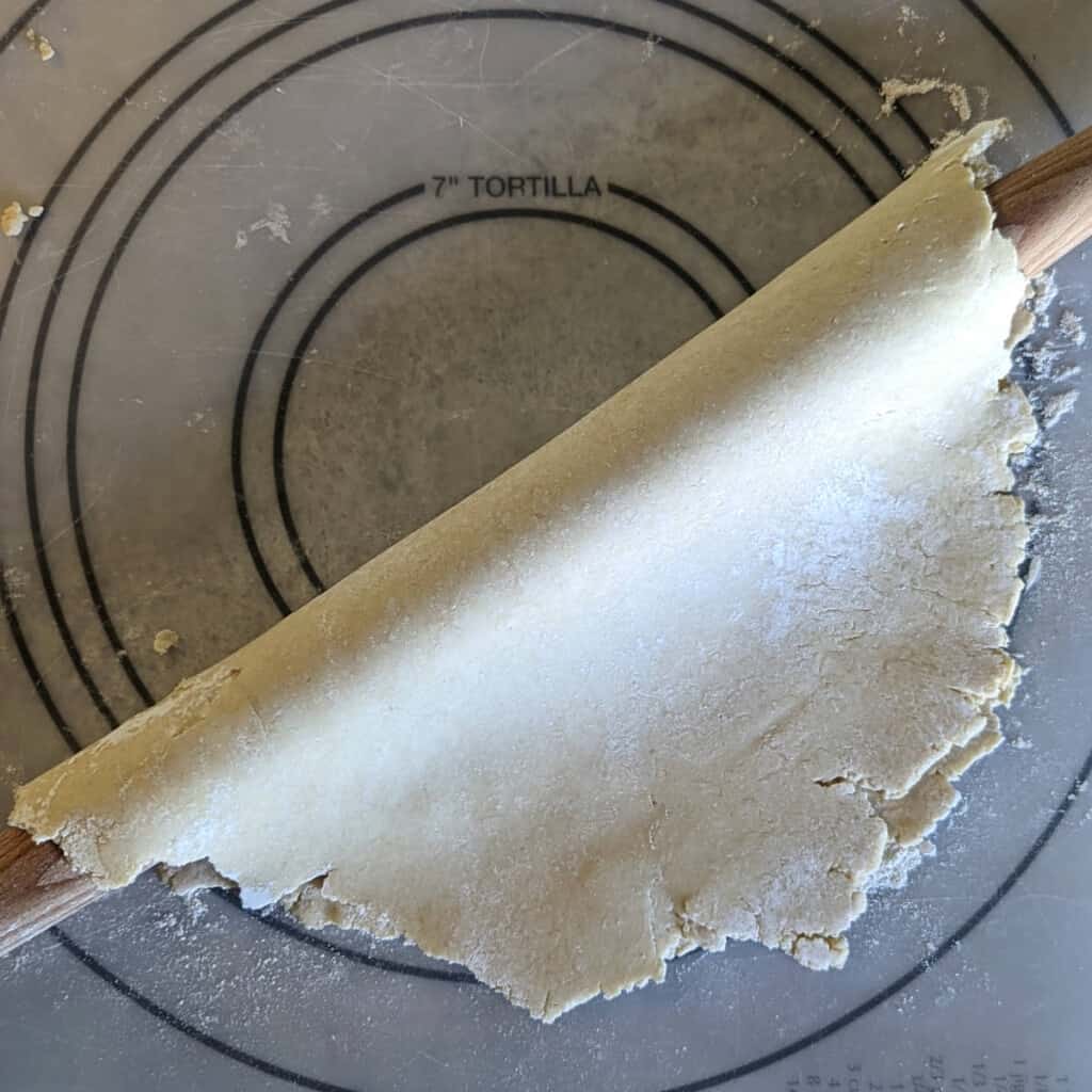 rolled out pie crust dough, folded in half over a rolling pin