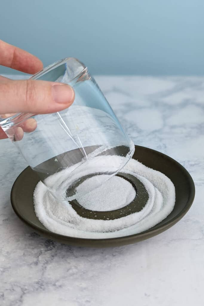 rolling a dampened glass rim in sugar