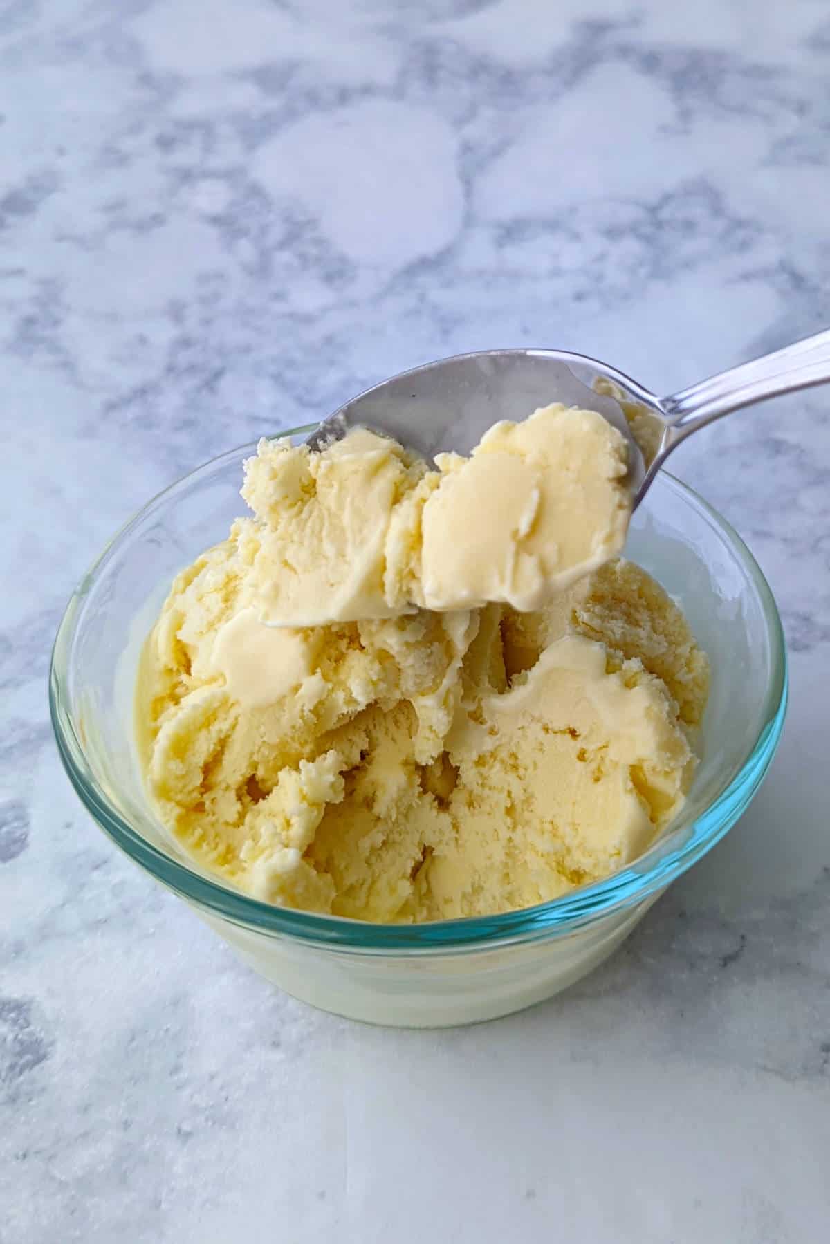 a bite of anise ice cream, on a spoon over a bowl of ice cream