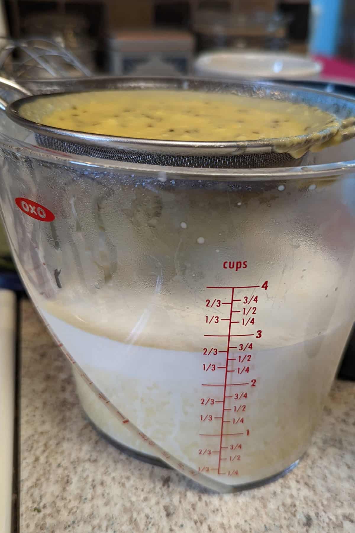 straining cooked custard through a sieve that is a little too small