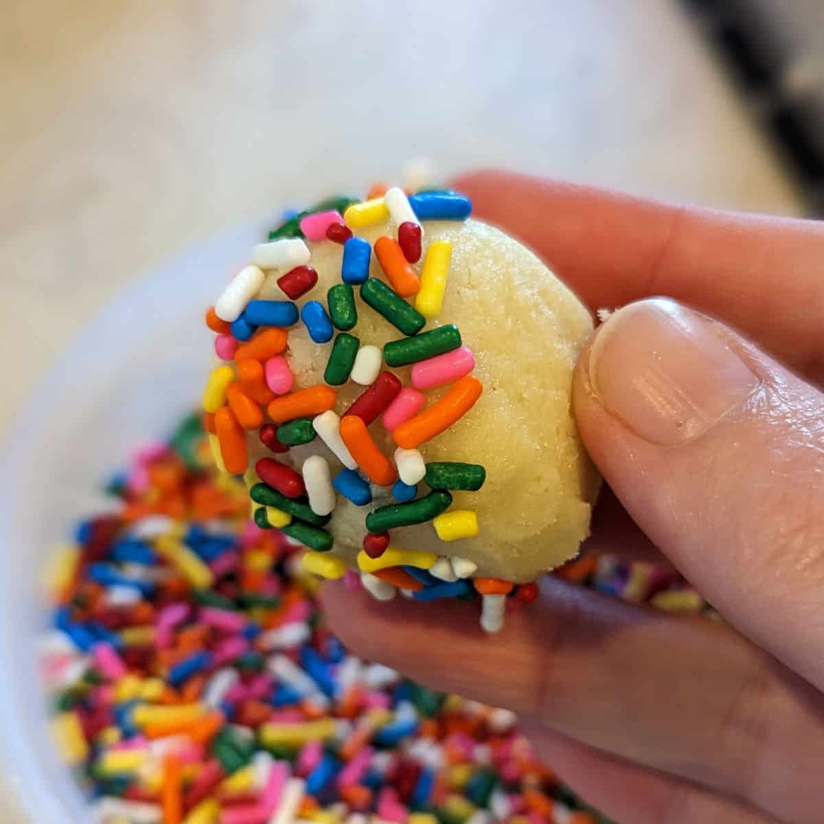 ball of cookie dough partially coated in sprinkles