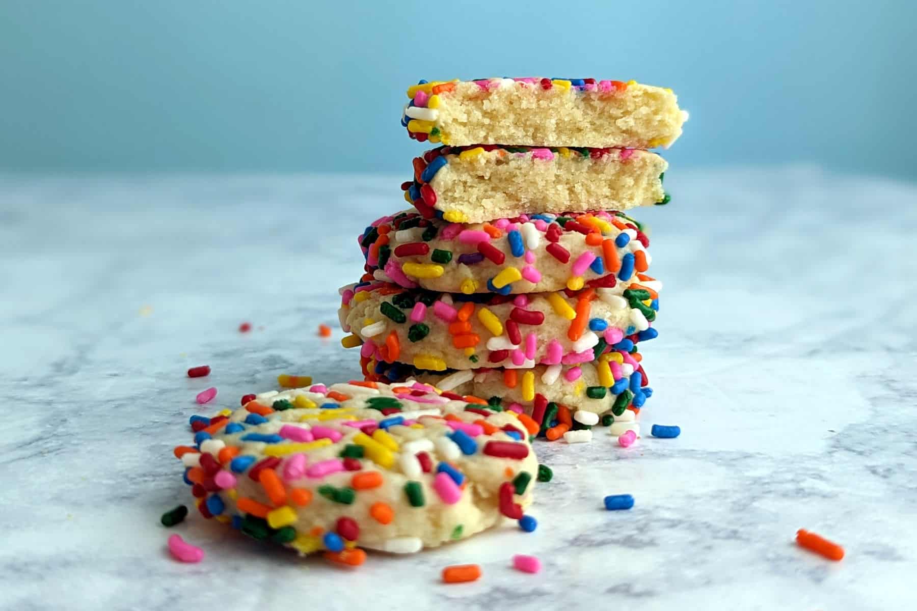 stack of sprinkle cookies, with one broken open to show texture