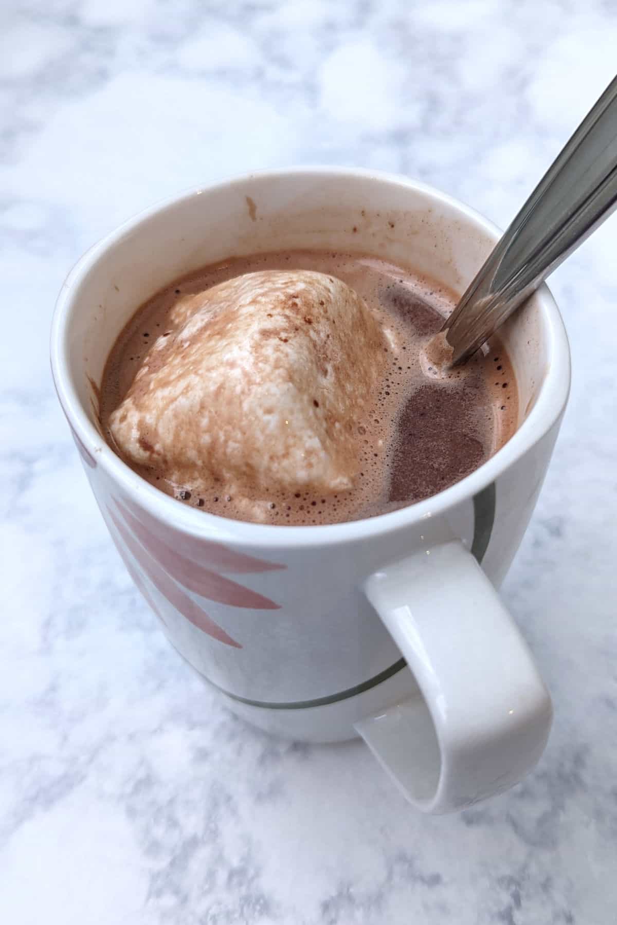 hot chocolate in a mug, with melted marshmallow and spoon