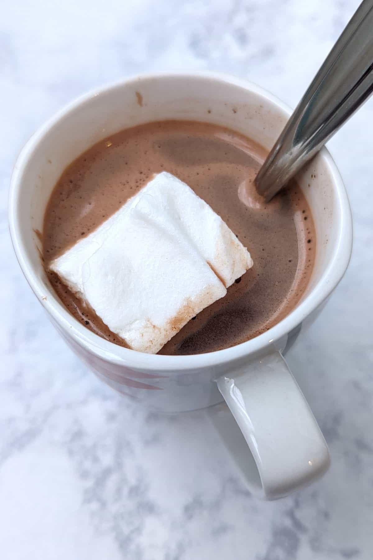 hot chocolate in a mug, with marshmallow and spoon