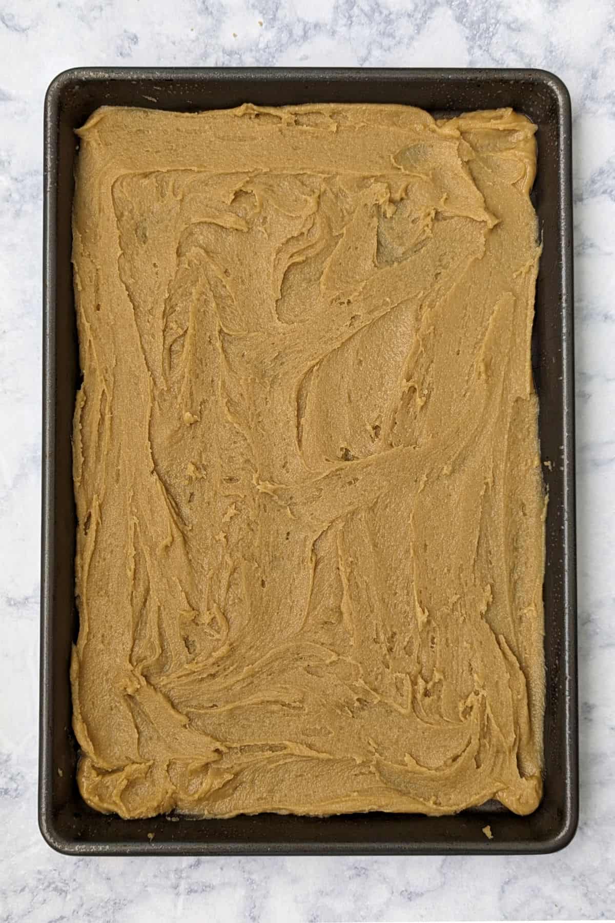 half of the butterscotch blondie batter in a jelly roll pan